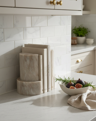 Kitchen counter with decorative items , bookends and a bowl of fruit.